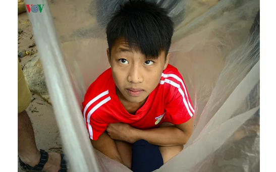 По дороге в школу, дети в деревне Вьетнама форсируют реку в пластиковых пакетах