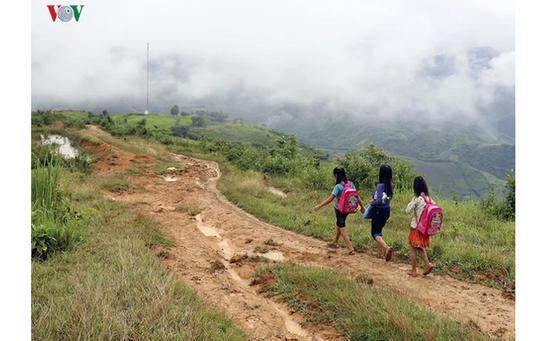По дороге в школу, дети в деревне Вьетнама форсируют реку в пластиковых пакетах